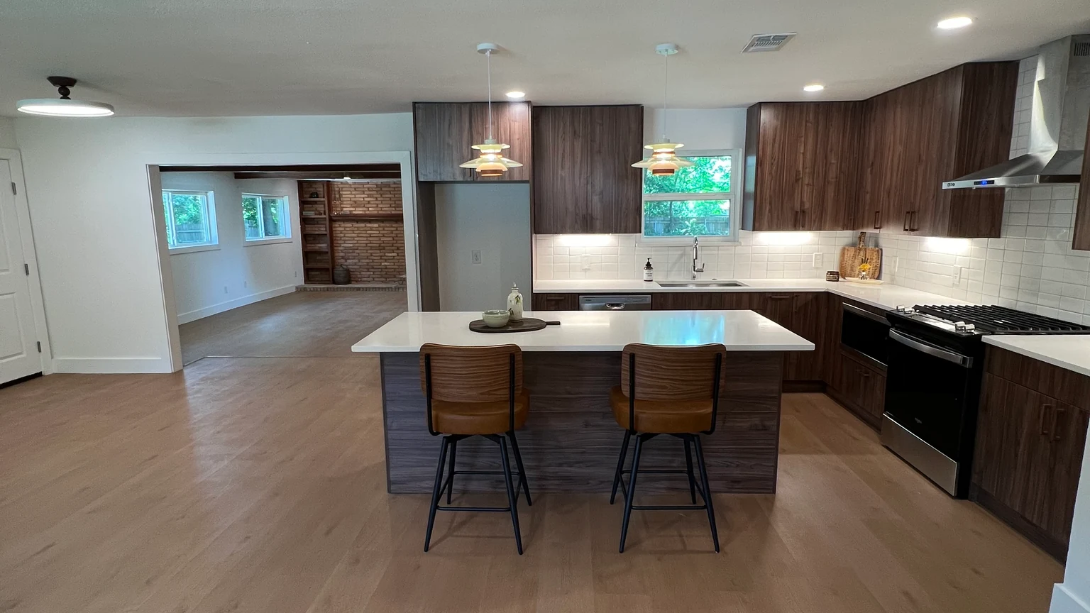 Completed kitchen remodel with wood cabinetry, island seating, and warm flooring